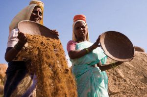 Two Indian women sifting through dirt