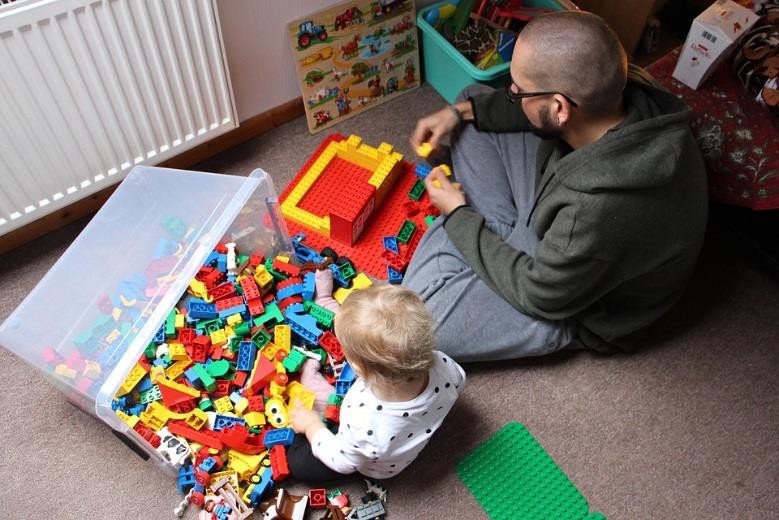 An adult playing Legos with a child.