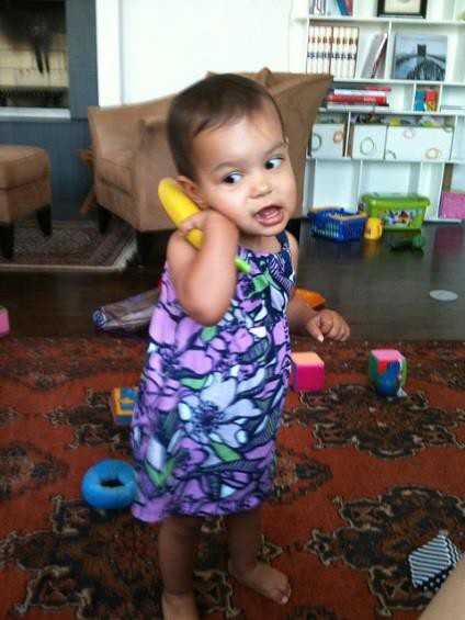A toddler playing with a toy telephone.