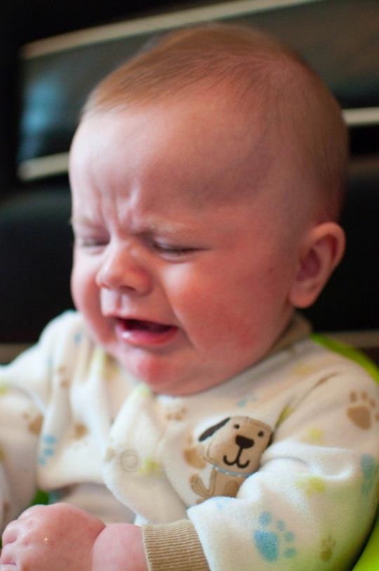 An infant making a sad facial expression.