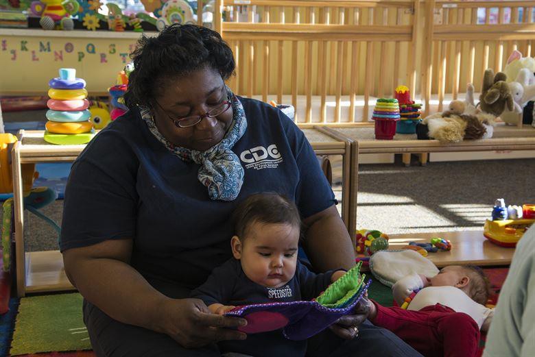A caretaker reading to an infant.