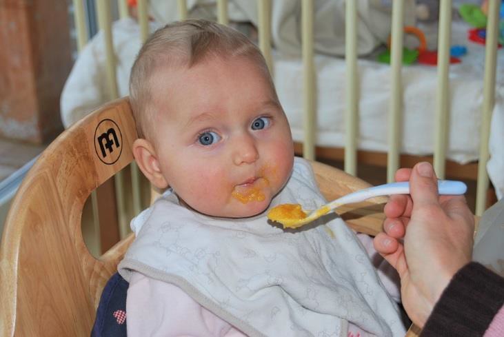 A baby being fed solid food.