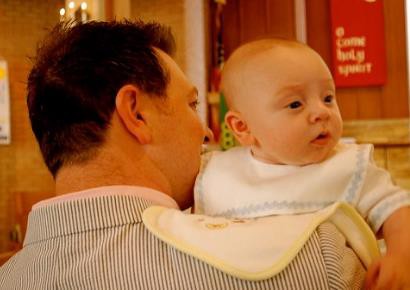 A father holding his baby with a cloth protecting his shoulder from spit-up.