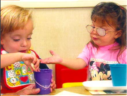 Two young children of different abilities eat together.