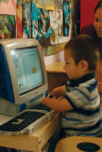 A child with unusually small hands is working on a computer as an adult watches.