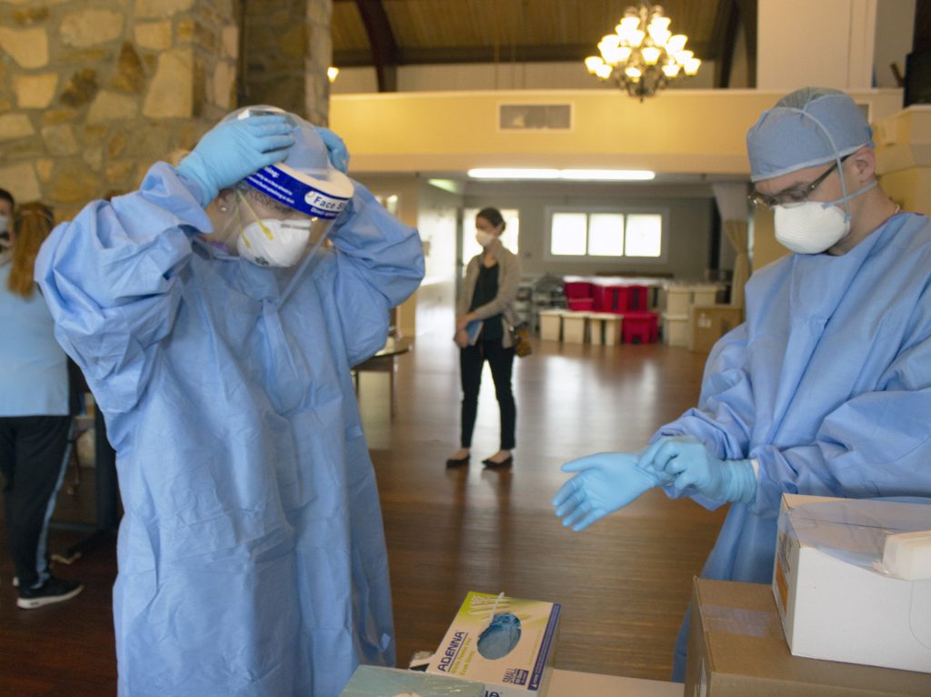 Photo of two people putting on personal protective equipment