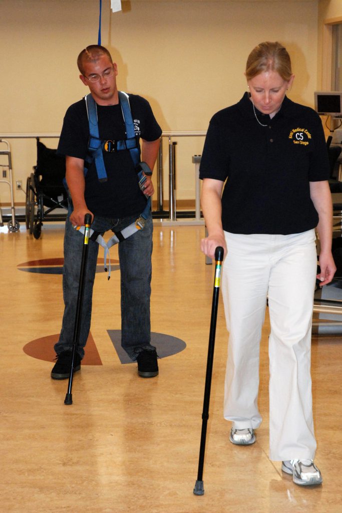 Timothy Jeffers walking with prosthetic legs and an assistive device