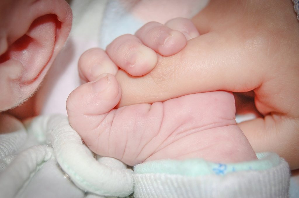 Photo of an infant grasping an person's fingers