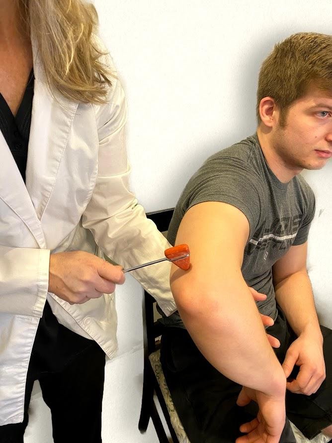 Photo showing nurse testing reflex on patient's tricep