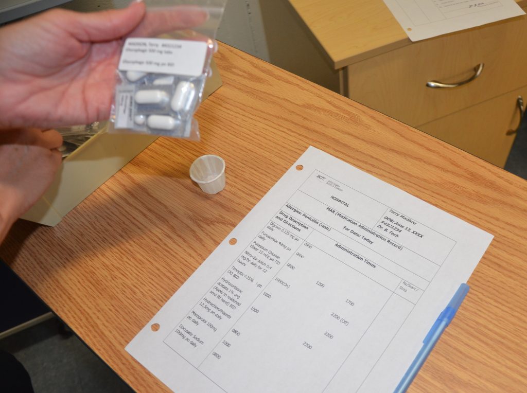 Photo showing a nurse checking information on pill bag matches what is on MAR