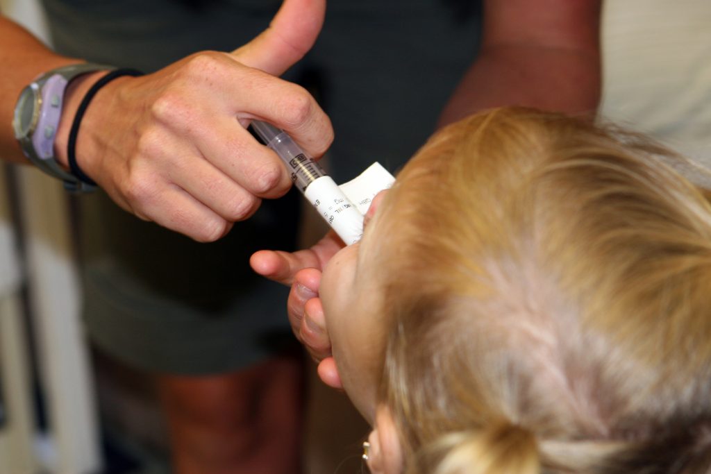 Photo of nurse administering oral medication with a syringe to a child