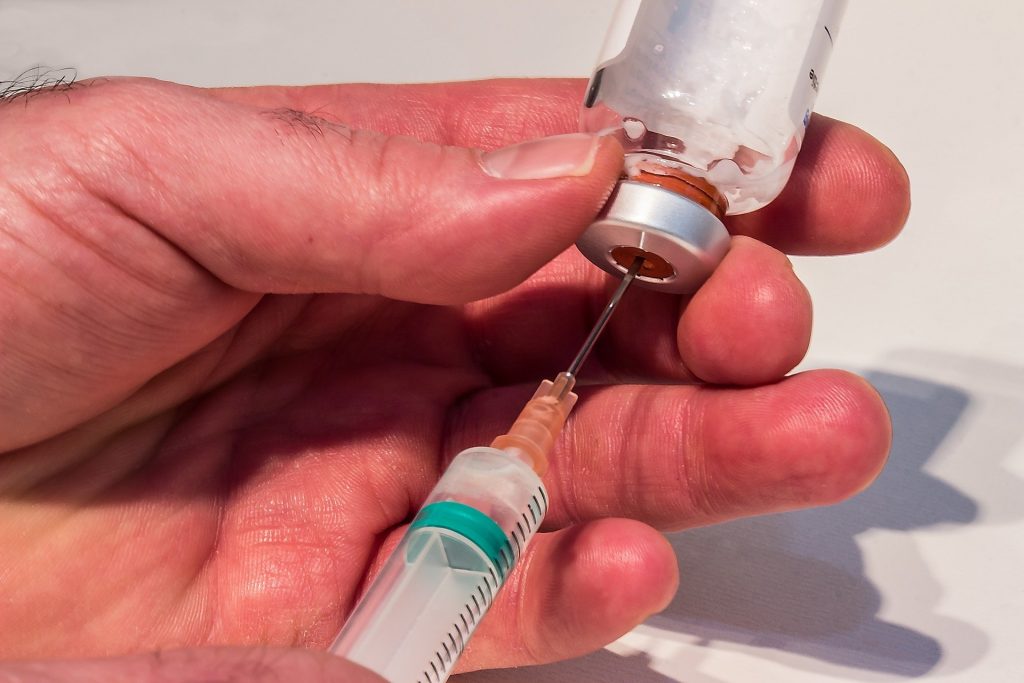 Photo of solution being removed from a vial with a syringe
