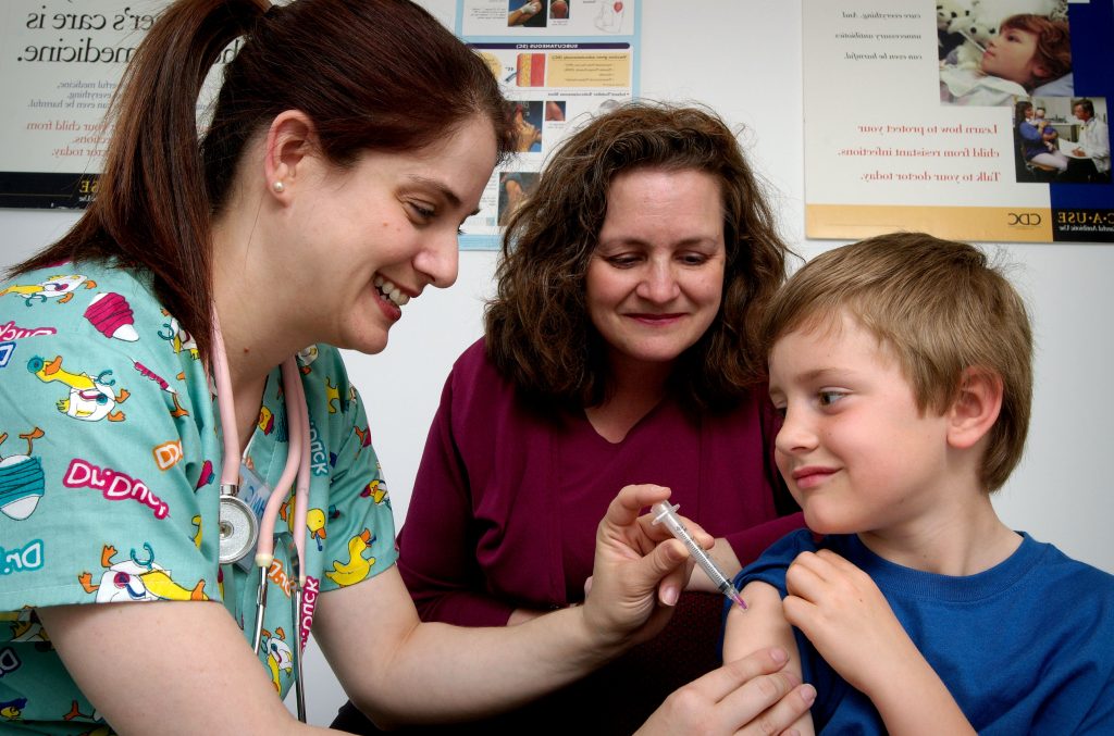Photo showing nurse administering an injection to a young patient