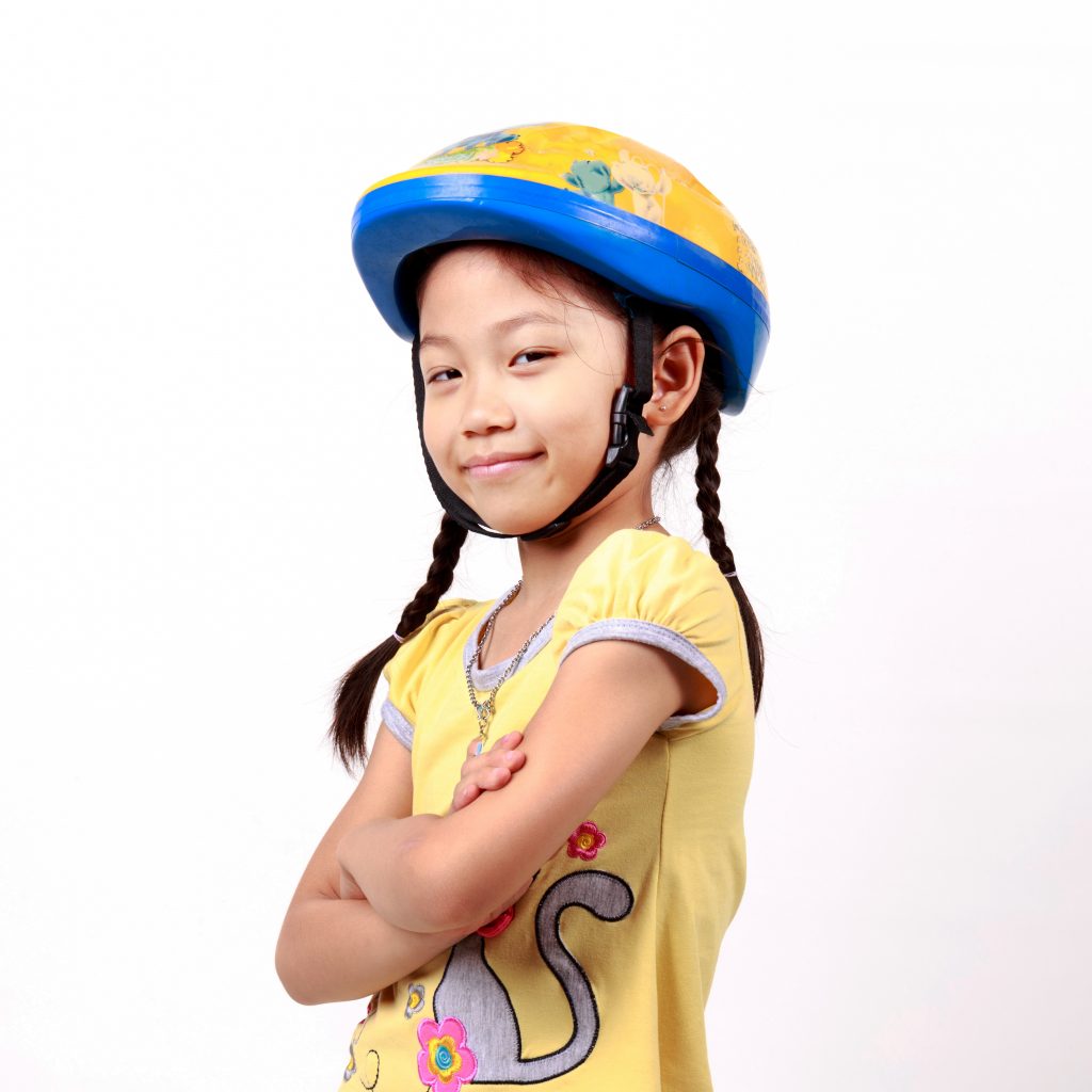 Image of young girl, with crossed arms, wearing a bicycle helmet and smiling