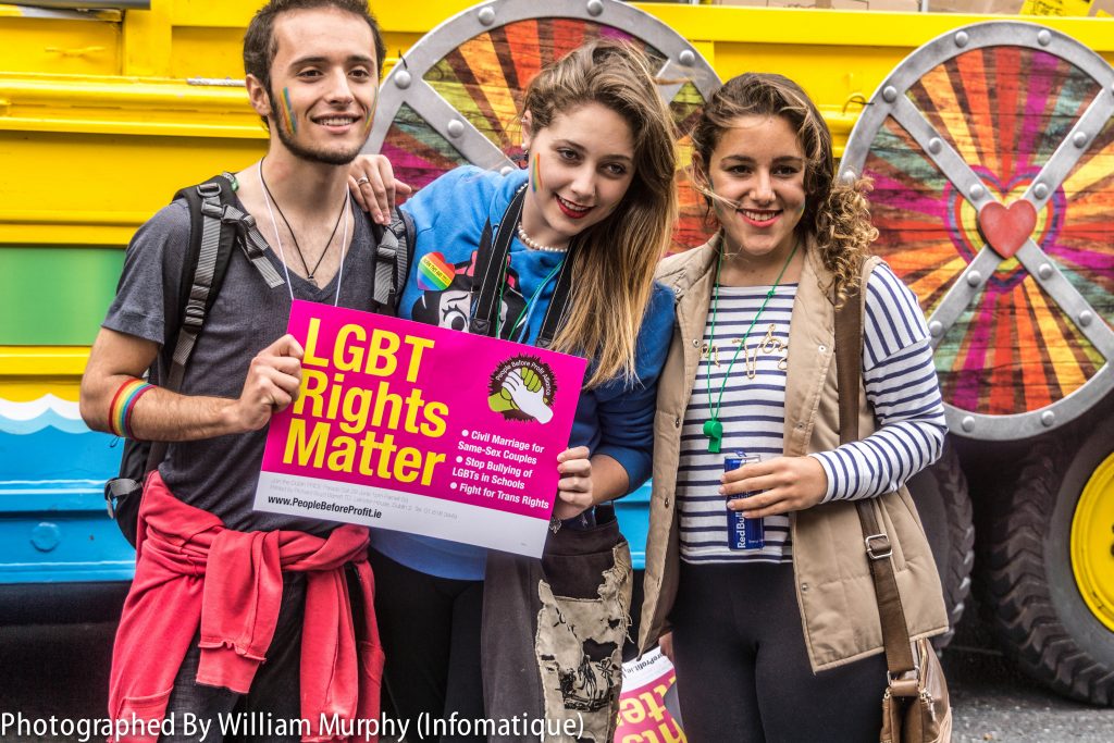 Photo showing three people at a LGBT rally