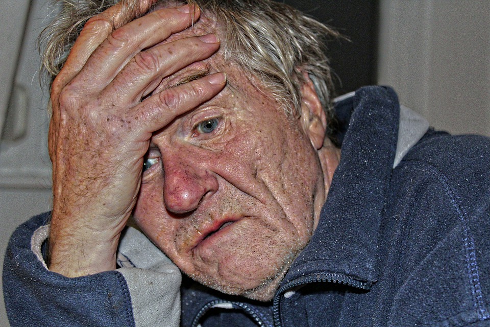 Image of older man with their hand on their forehead.