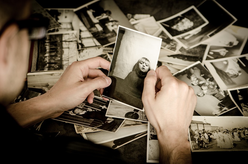 Image showing person off camera looking at photo of a child, with photos on ground in background