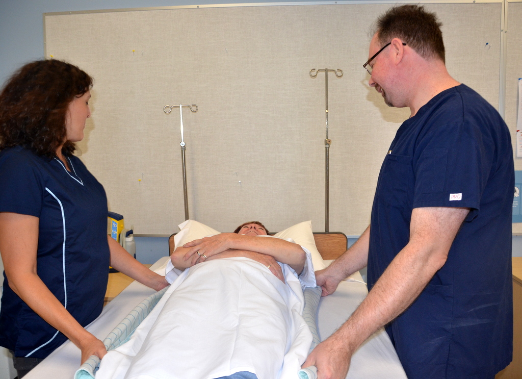 Image showing two nurses moving a simulated patient up in a bed