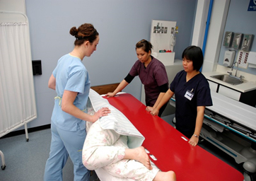 Image showing three medical staff positioning a patient on a slider board