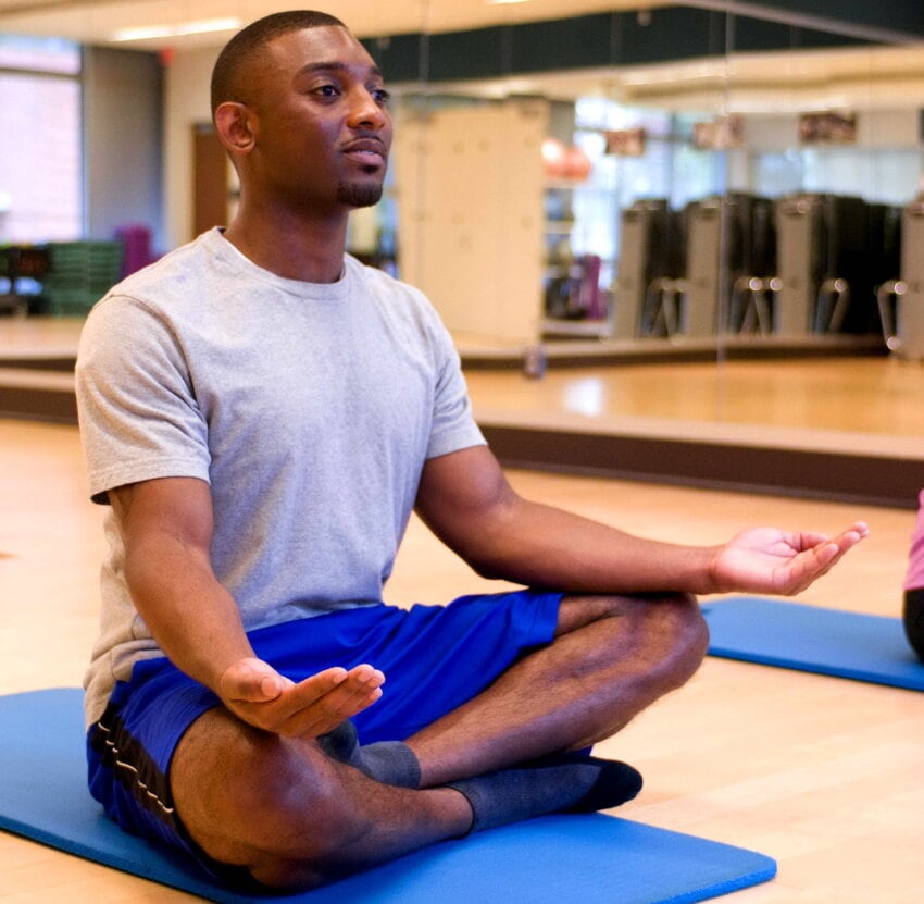 Photo showing a person meditating with eyes open and palms up, while sitting cross legged