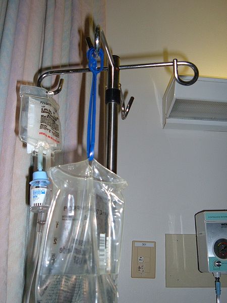 Photo showing the top portion of an IV pole with fluid bags deployed
