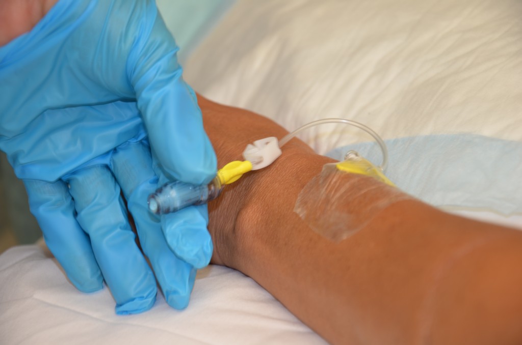 Photo showing a gloved hand holding a saline lock