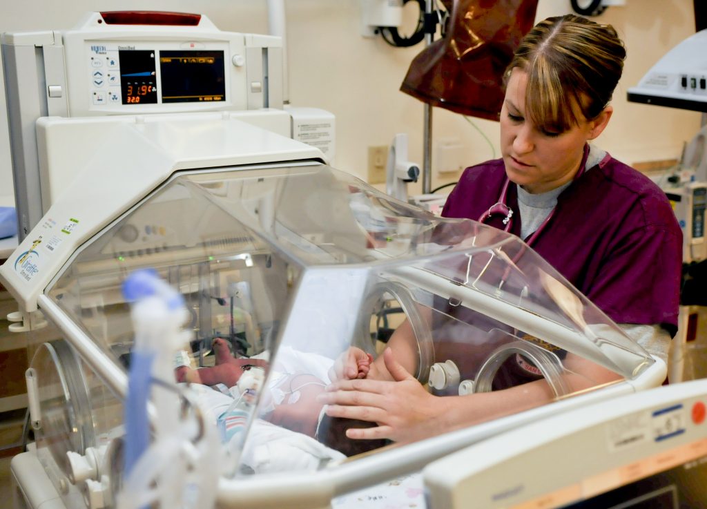 Photo showing a nurse using therapeutic touch on a newborn