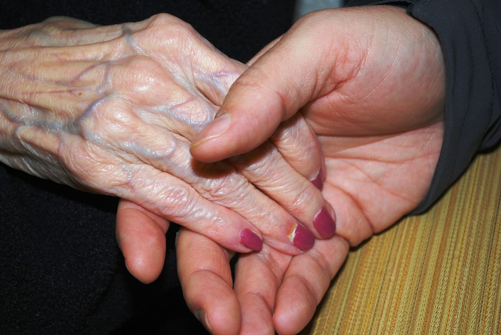 Photo showing closeup of older looking hand being held by younger looking hand