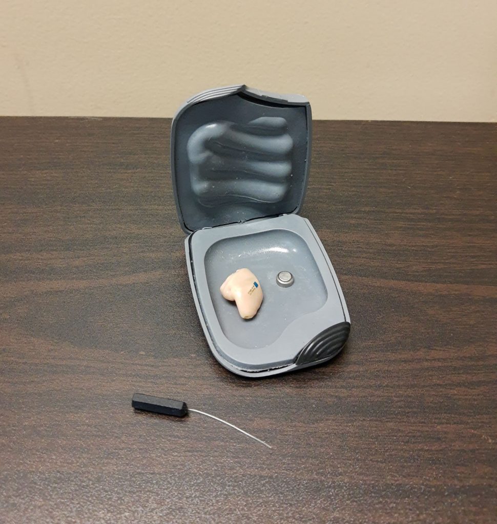 Photos showing Hearing Aid in a Case With a Battery and Cleaning Tool