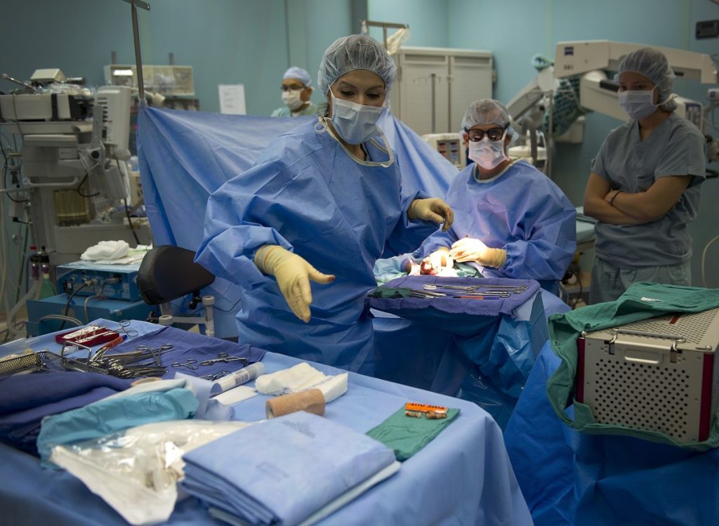 Image showing a surgery team, one person reaching for surgical instruments that are set up on a sterile field in the foreground