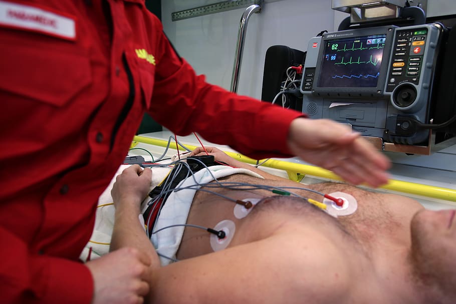 Image showing a medical personnel performing an ECG on a patient, with the monitor in the background