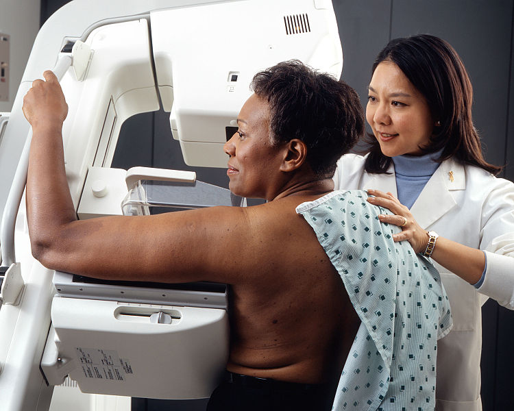 Image showing a technician helping a patient undergo a mammogram