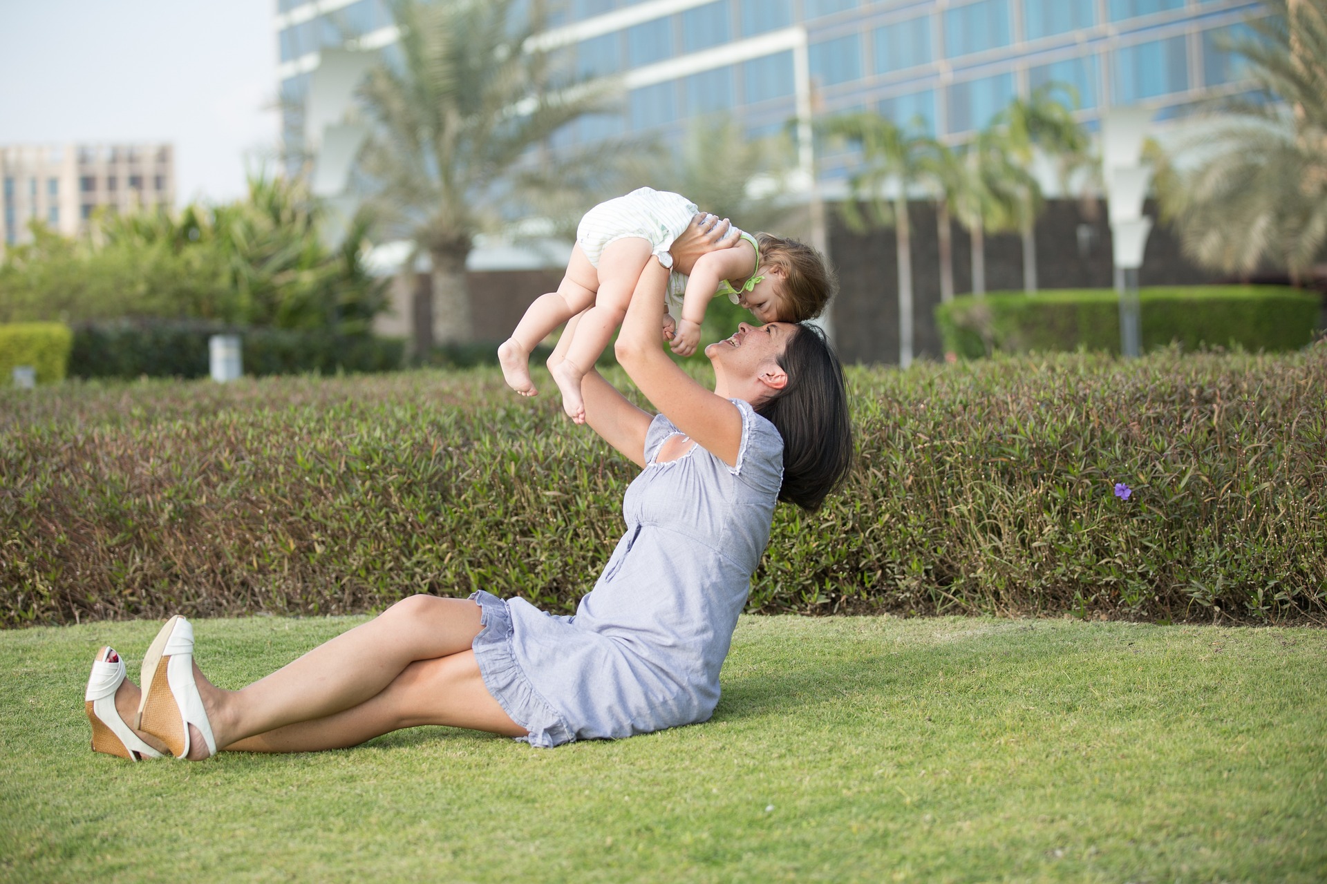 Image showing a mother and child in an outdoor setting, mom sitting while lifting up child