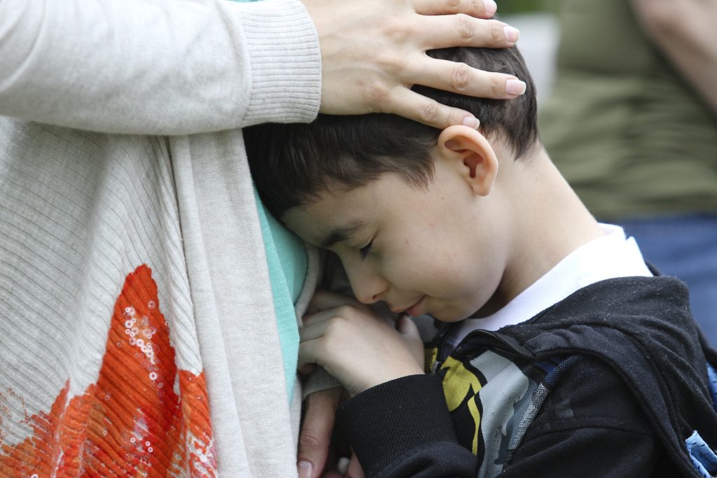 A young boy is comforted by his mother during a departure ceremony for the Army Reserve