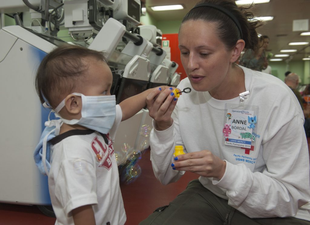 Anne Bordal, a Childlife Specialist volunteer with Project Smile, plays with a Filipino child aboard the Military Sealift Command hospital ship USNS Mercy (T-AH 19) during Pacific Partnership 2015