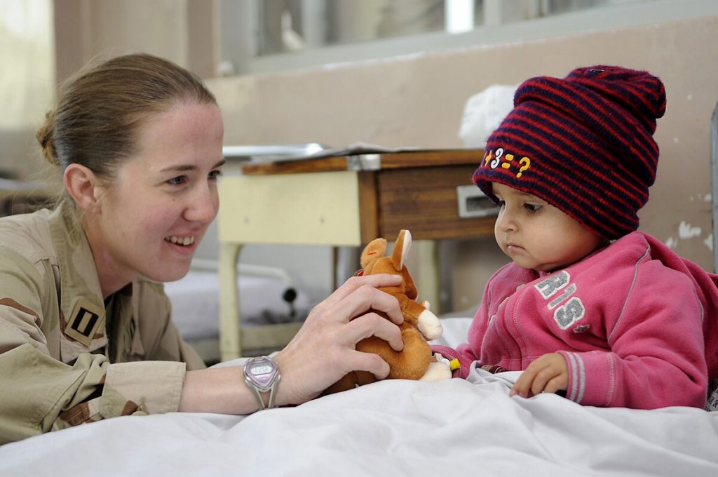 United States Navy Lt. Jessica Gandy gives a stuffed kangaroo to cheer up an Afghan girl in the Indira Gandhi Children's Hospital Burn Ward while international service members also assigned to International Security Assistance Force Headquarters pass out other stuffed animals and crayons to the burn victims, downtown Kabul, Afghanistan, Nov. 20.