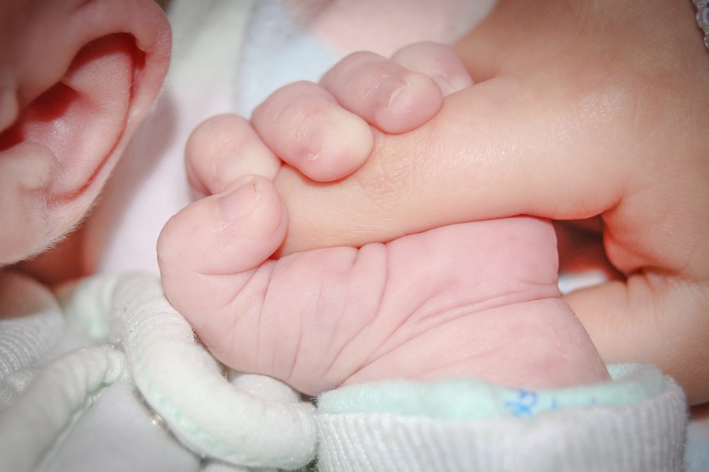 Photo showing an infant grasping an adult finger