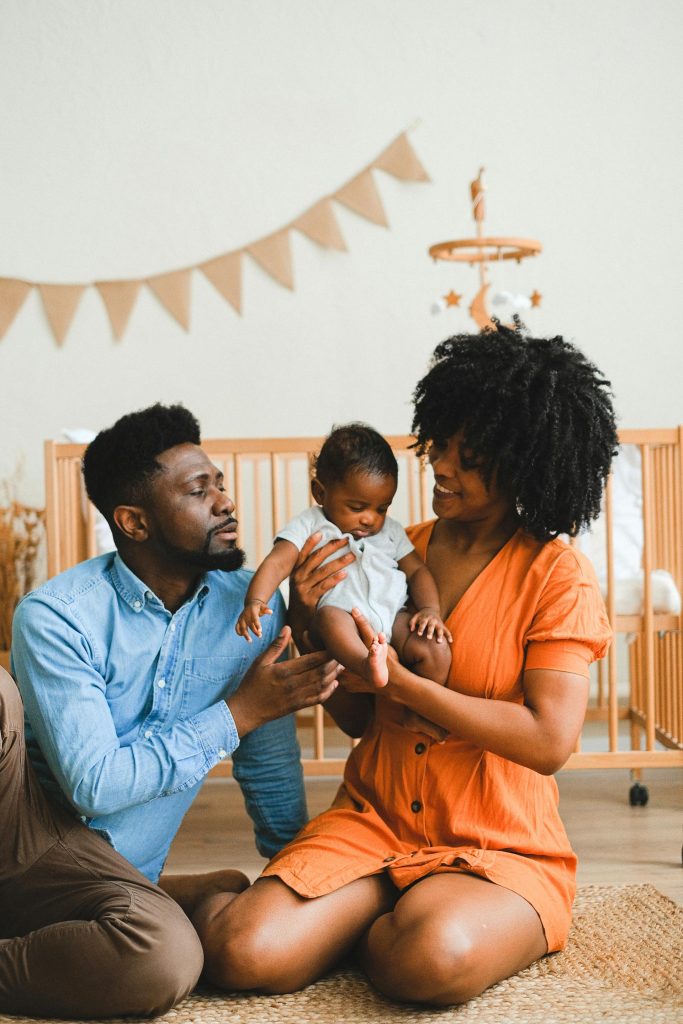 Photo showing two adults interacting with an infant