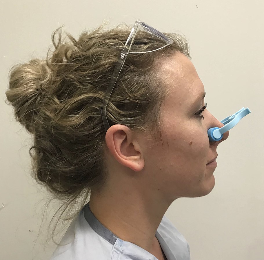 Photo showing a person using a nasal clip to stop a nosebleed