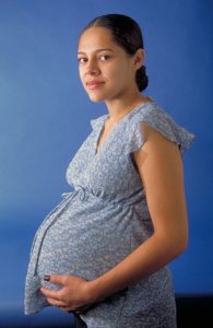 Photo showing a pregnant woman looking towards the viewer