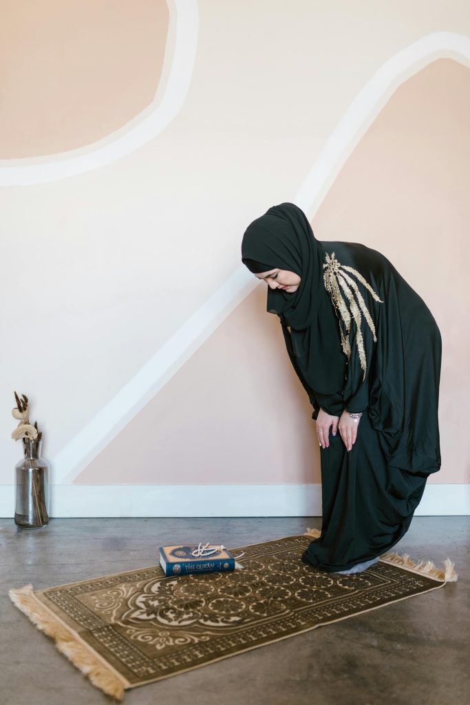 Photo showing a Muslim woman standing on a prayer rug