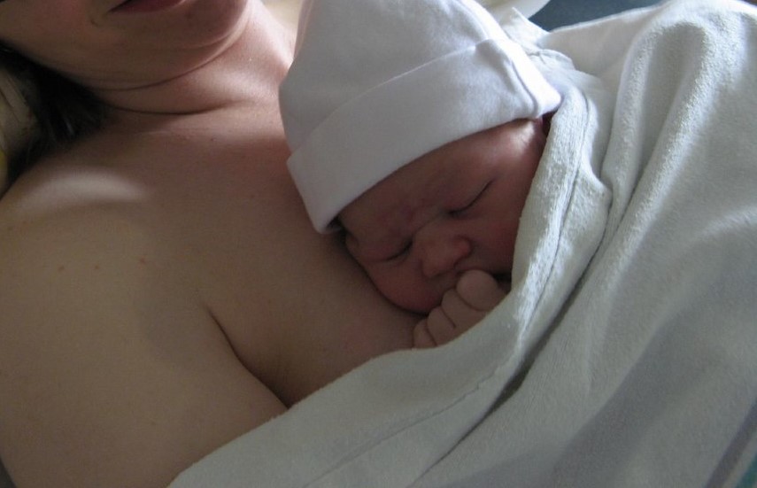 Photo showing a newborn laying on it's mother's bare chest