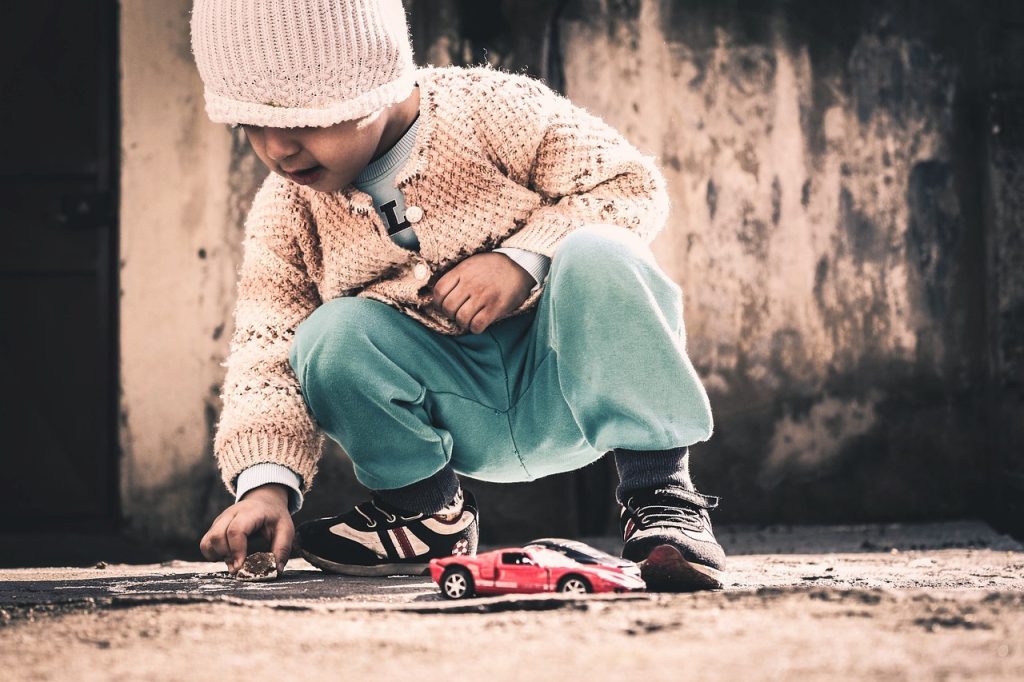 Photos showing a young child playing with toy cars outside