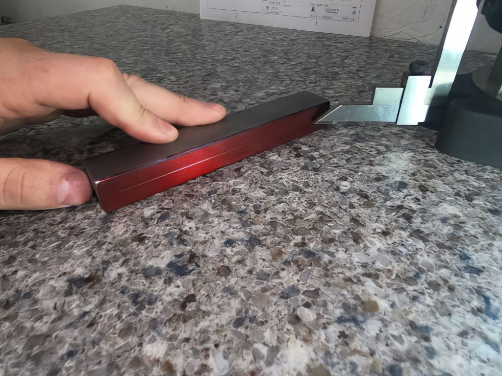 Hand shown creating a scribe line using a surface plate and height gage