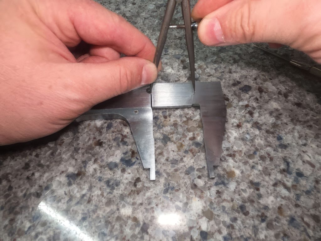 Hands holding a spring divider on top of a caliper