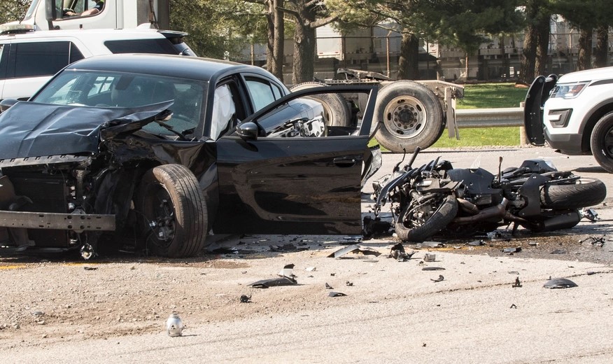 An collision scene involving a motorcycle and a car.  Both vehicles show extensive damage.