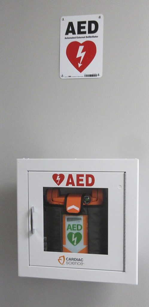 An automated external defibrillator in compartment with sign above
