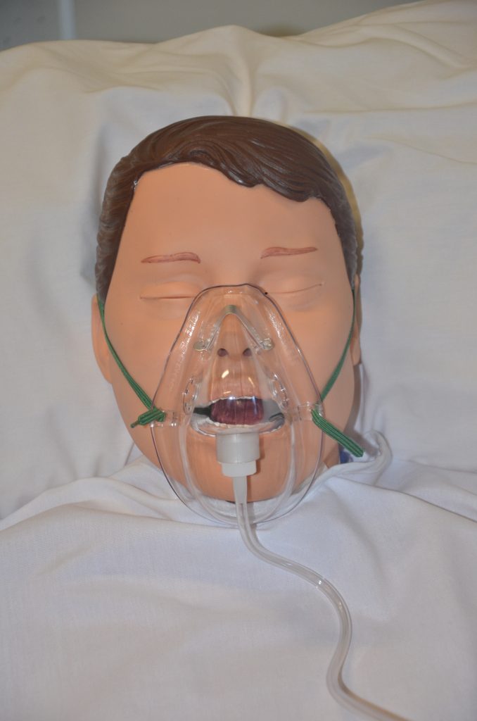 A simulated patient is wearing a simple mask