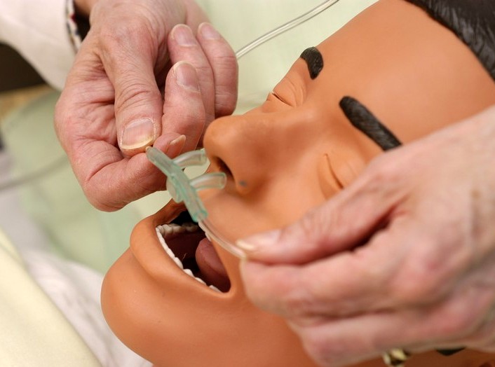 An nasal canula is being placed on a simulated patient