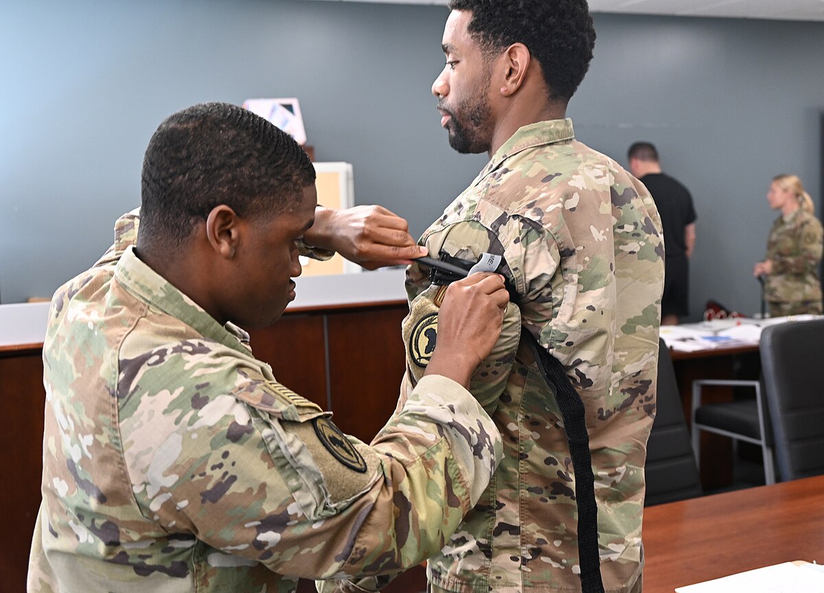 Military personnel are practicing the application of a tourniquet to the upper arm
